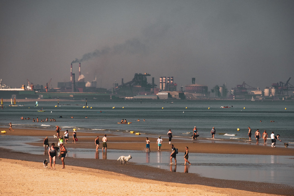 Menschen am Strand vor industrieller Kulisse