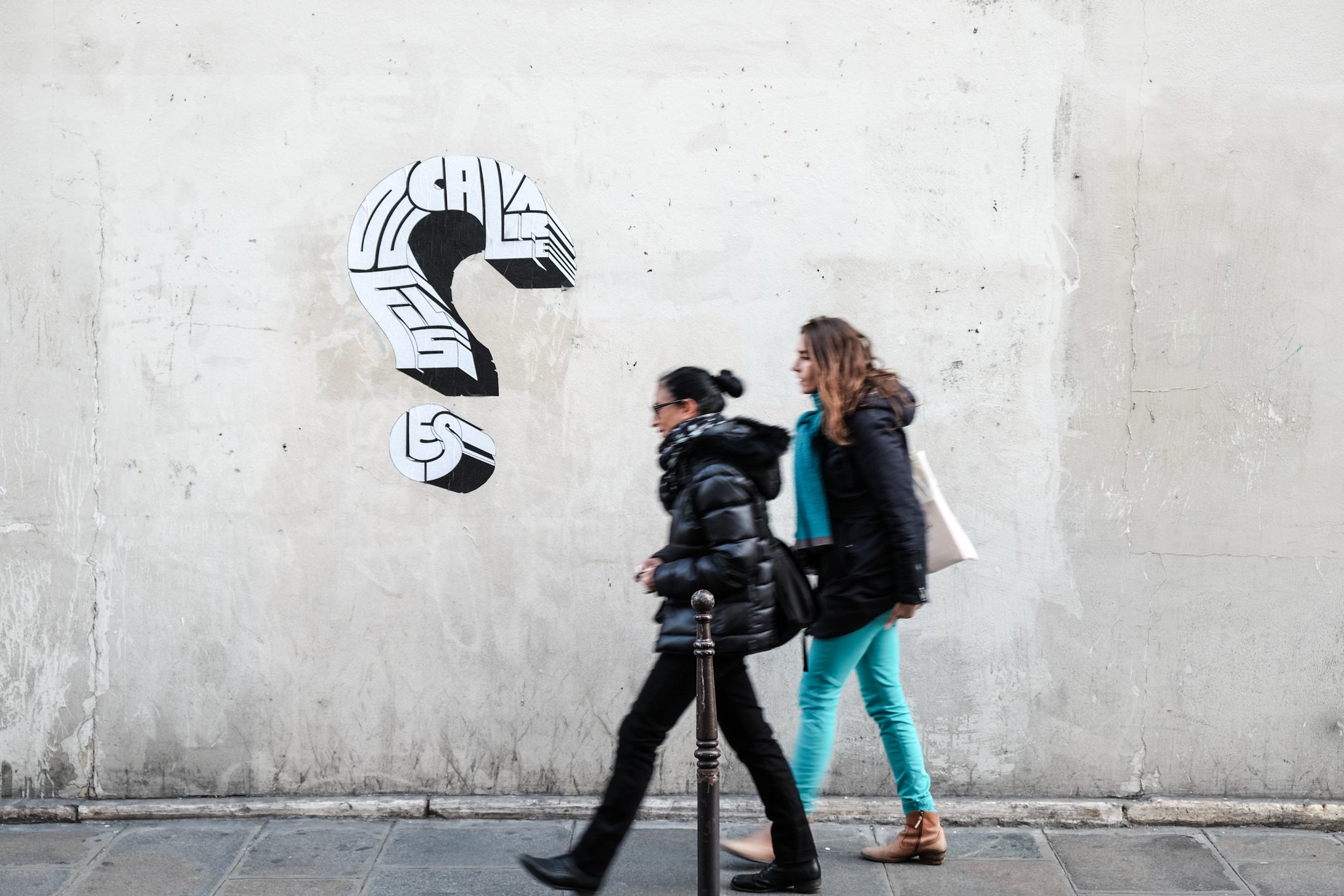 Streetfotografie Workshop in Düsseldorf, zwei Frauen vor einer Wand mit Stencil Kunst und ein Fragezeichen